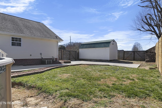 view of yard featuring a storage unit, an outdoor structure, a fenced backyard, and a gate