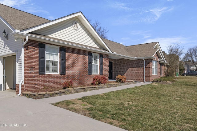 view of front of property featuring roof with shingles, a front lawn, and brick siding