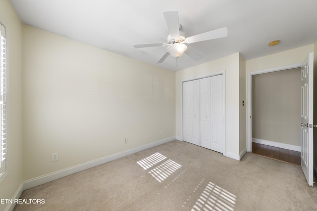 unfurnished bedroom with a ceiling fan, baseboards, a closet, and light colored carpet