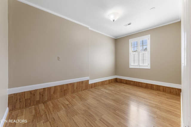 unfurnished room featuring ornamental molding, visible vents, and light wood-style floors