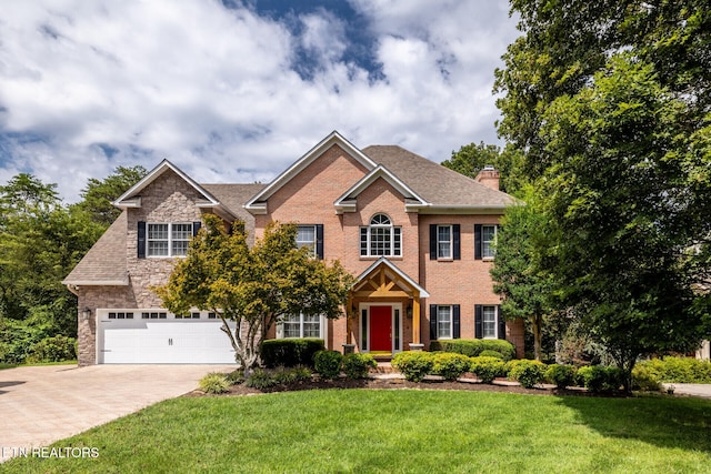 view of front of house featuring brick siding, decorative driveway, and a front lawn