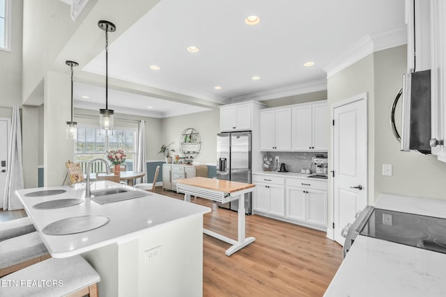 kitchen with crown molding, a breakfast bar area, stainless steel appliances, white cabinetry, and a sink