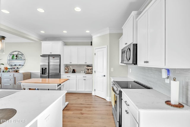 kitchen featuring crown molding, stainless steel appliances, light wood-type flooring, and white cabinets