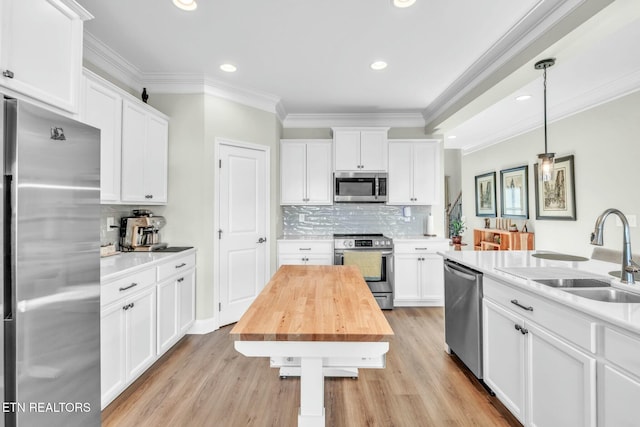 kitchen featuring stainless steel appliances, a sink, wooden counters, and white cabinets
