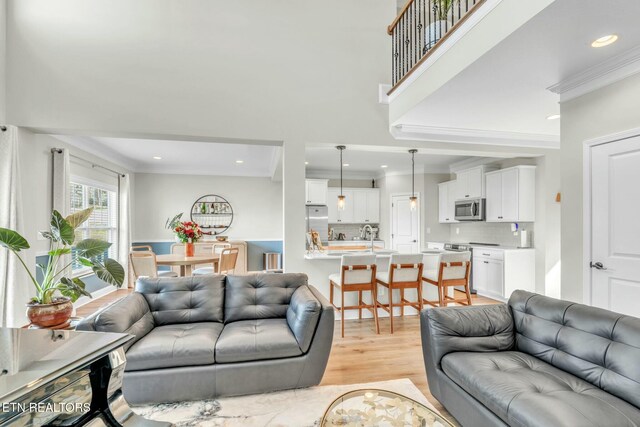 living room with light wood-style floors, ornamental molding, and recessed lighting