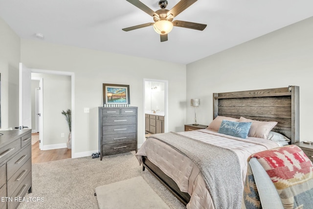 bedroom with light carpet, ceiling fan, ensuite bathroom, and baseboards