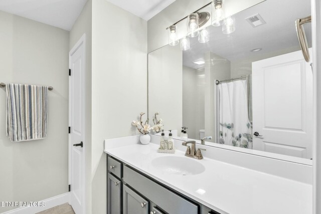 full bathroom featuring curtained shower, toilet, vanity, visible vents, and baseboards