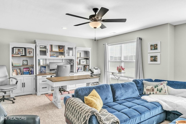 living area featuring light carpet and ceiling fan