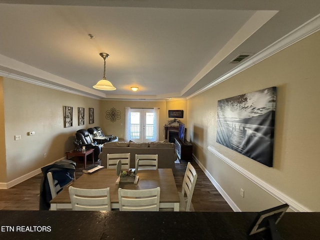 dining space with dark wood-style flooring, a raised ceiling, visible vents, and baseboards