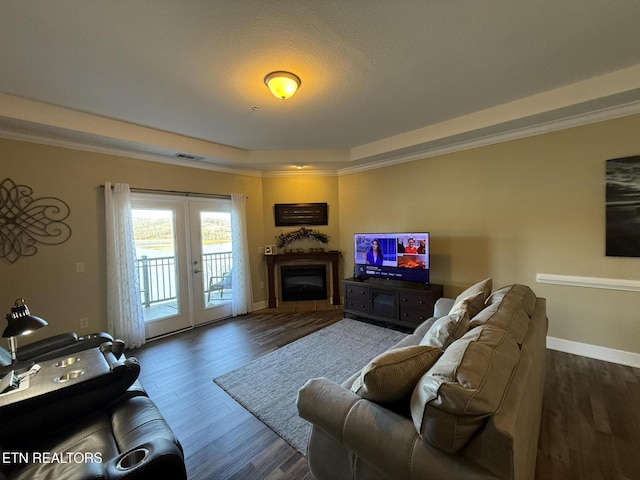 living area featuring visible vents, dark wood-style floors, a tray ceiling, french doors, and a fireplace