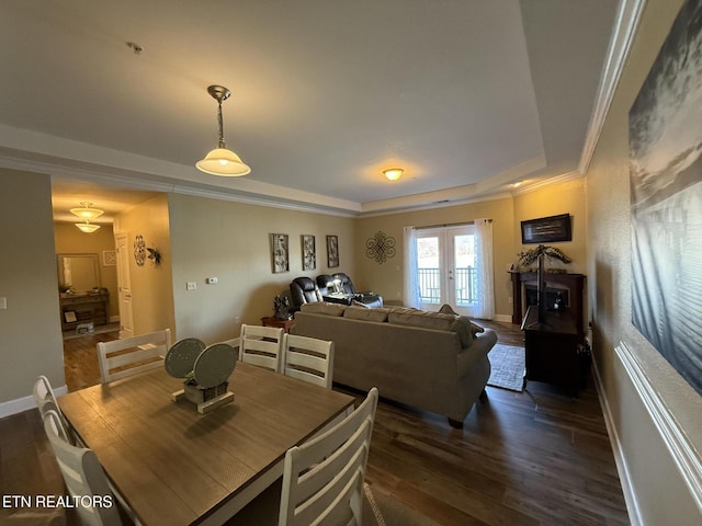 dining room with dark wood-type flooring, baseboards, french doors, a raised ceiling, and crown molding