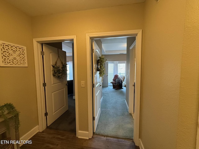 hallway featuring dark wood finished floors and baseboards