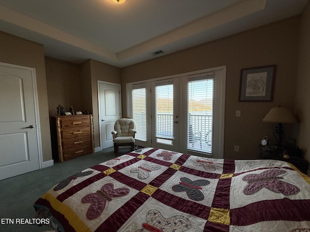 carpeted bedroom with a tray ceiling, french doors, visible vents, and access to exterior