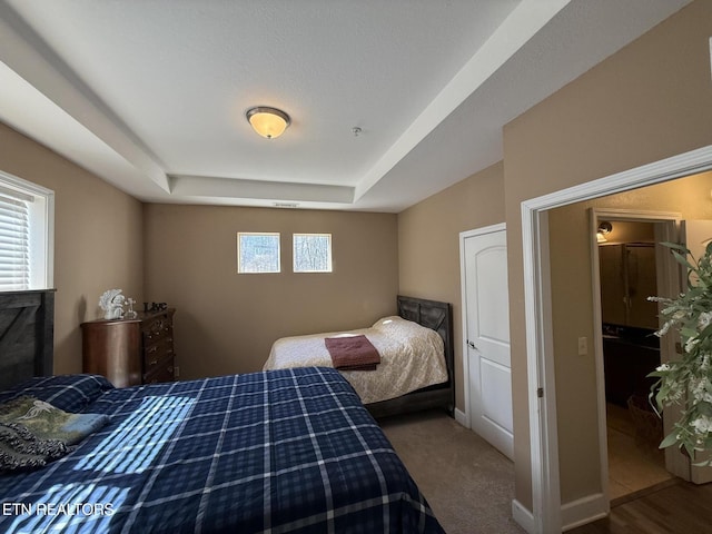 bedroom with multiple windows, a raised ceiling, and baseboards