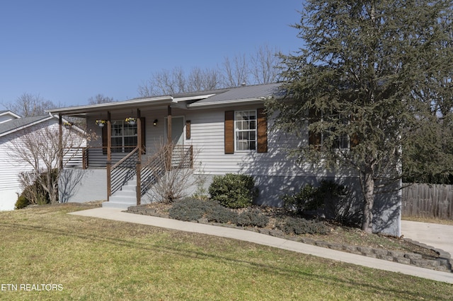 ranch-style home with metal roof, covered porch, a front lawn, and fence