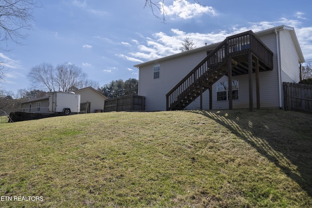 exterior space with stairway, a yard, a wooden deck, and fence