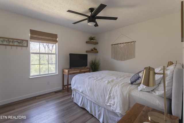 bedroom with baseboards, a textured ceiling, wood finished floors, and a ceiling fan