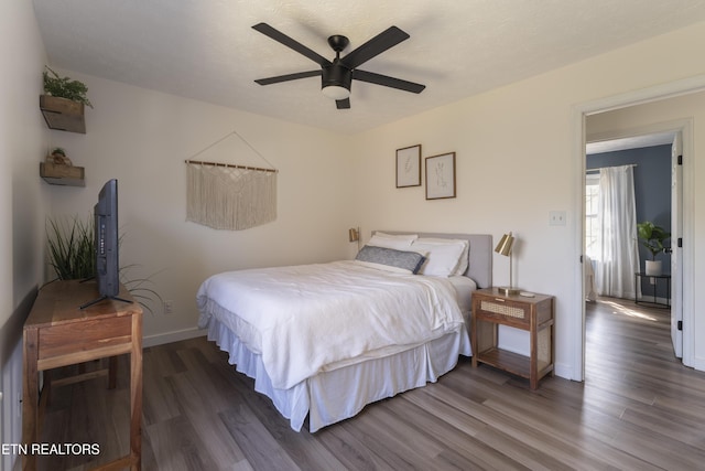 bedroom with ceiling fan, baseboards, and wood finished floors