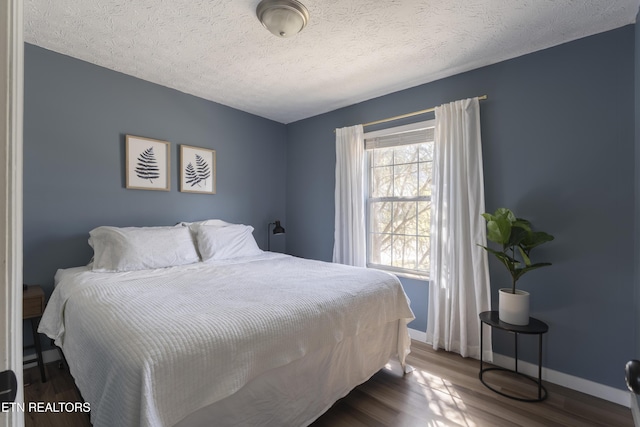 bedroom featuring baseboards, a textured ceiling, and dark wood-style floors