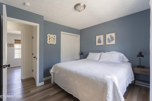 bedroom featuring a closet, baseboards, a textured ceiling, and wood finished floors