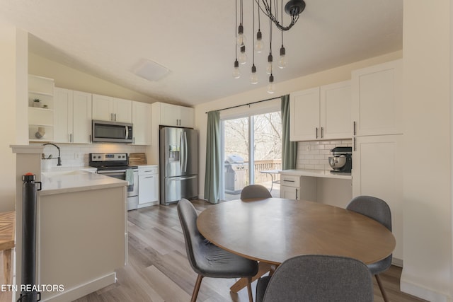 kitchen with open shelves, white cabinetry, stainless steel appliances, light countertops, and vaulted ceiling