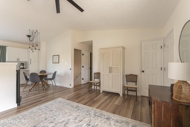 living area featuring ceiling fan, baseboards, light wood-style floors, and vaulted ceiling