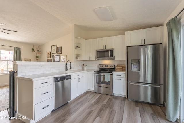 kitchen featuring open shelves, appliances with stainless steel finishes, a peninsula, and light countertops