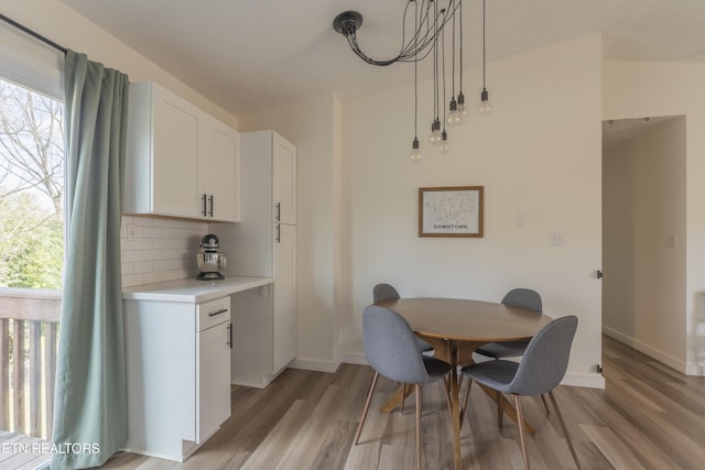 dining area with light wood-style flooring, a healthy amount of sunlight, and baseboards