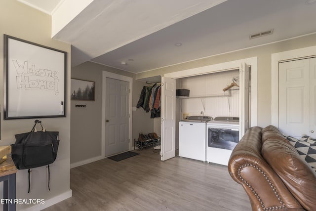 laundry area featuring visible vents, wood finished floors, baseboards, laundry area, and washing machine and clothes dryer