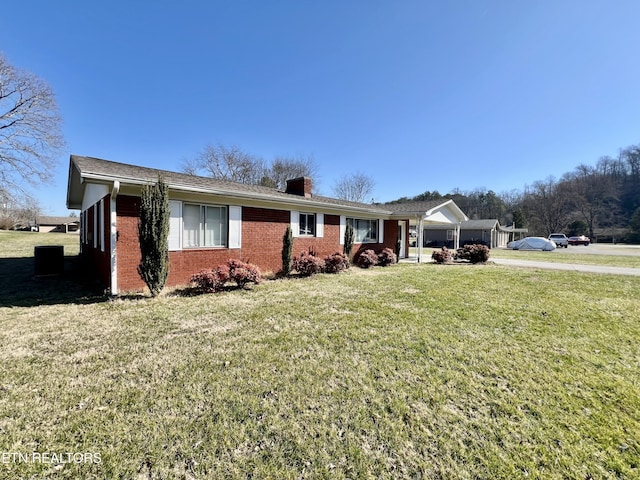 ranch-style home with brick siding, a chimney, and a front yard