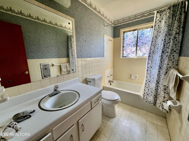 full bathroom featuring toilet, a wainscoted wall, vanity, tile walls, and shower / bath combo