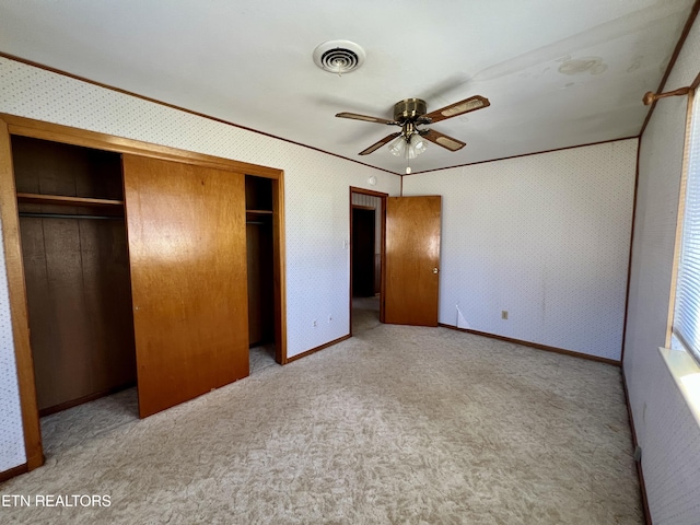 unfurnished bedroom with light carpet, visible vents, baseboards, a closet, and wallpapered walls