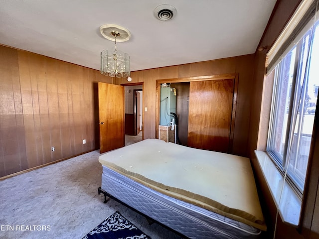 bedroom with a notable chandelier, a closet, visible vents, carpet flooring, and wooden walls