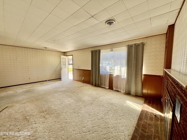 spare room featuring carpet floors, wainscoting, visible vents, and wallpapered walls