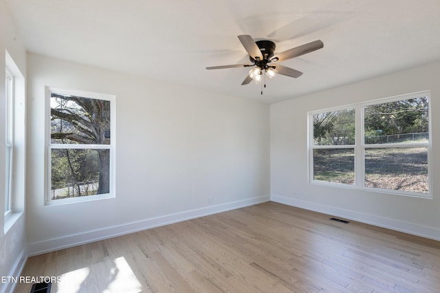 empty room featuring ceiling fan, baseboards, visible vents, and light wood-type flooring