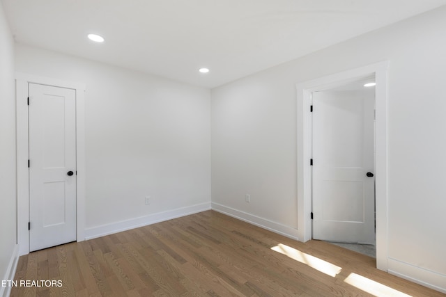 spare room featuring recessed lighting, wood finished floors, and baseboards