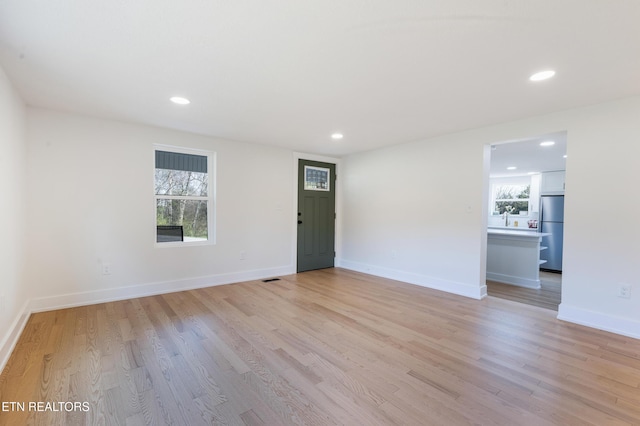 empty room featuring recessed lighting, light wood-type flooring, baseboards, and visible vents