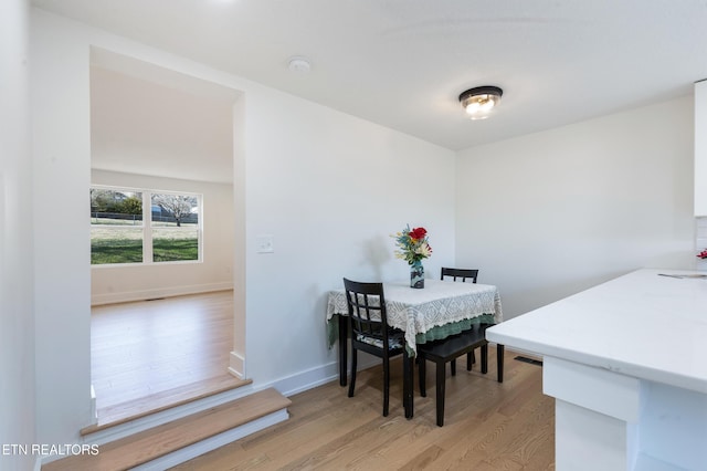 dining space featuring baseboards and light wood-style flooring