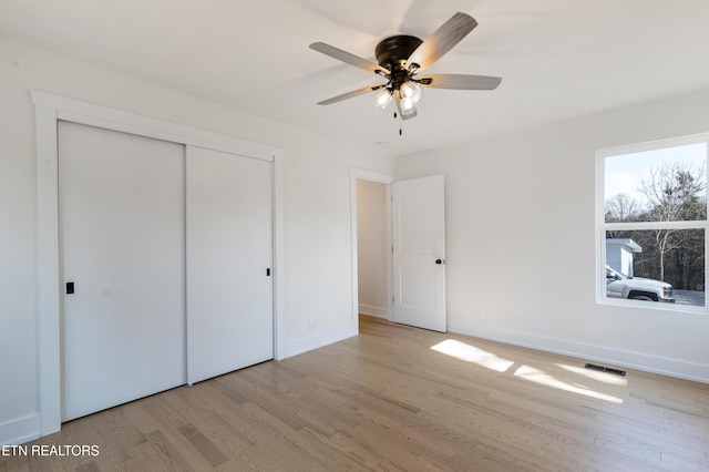 unfurnished bedroom with a closet, visible vents, baseboards, and wood finished floors