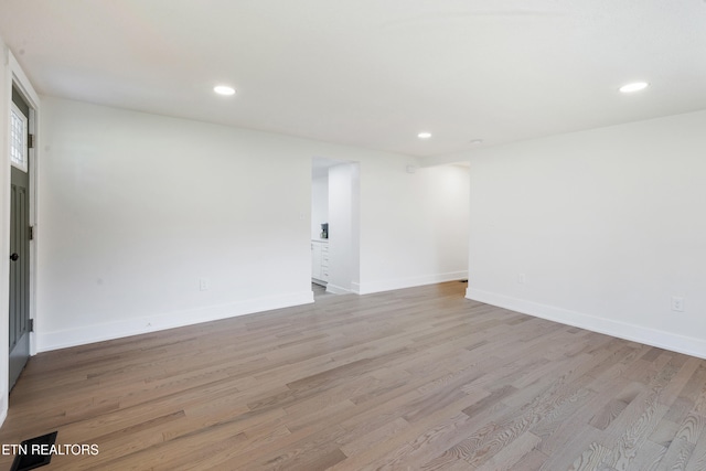 empty room with recessed lighting, light wood-type flooring, and baseboards