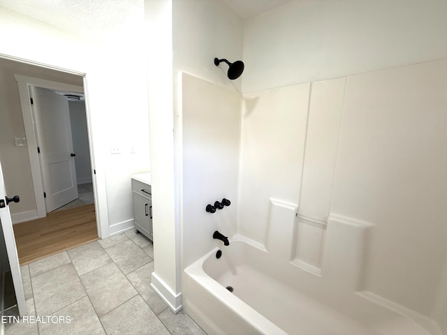 bathroom featuring vanity, tile patterned floors, washtub / shower combination, and baseboards