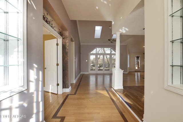 foyer with ceiling fan, baseboards, light wood-style flooring, and ornate columns