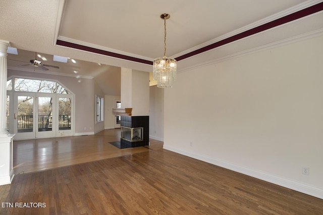 unfurnished living room with ceiling fan with notable chandelier, wood finished floors, a multi sided fireplace, baseboards, and crown molding