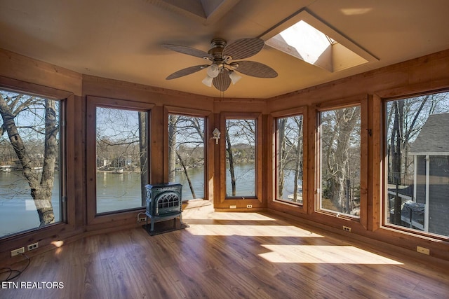 unfurnished sunroom featuring a skylight, a wood stove, a water view, and plenty of natural light