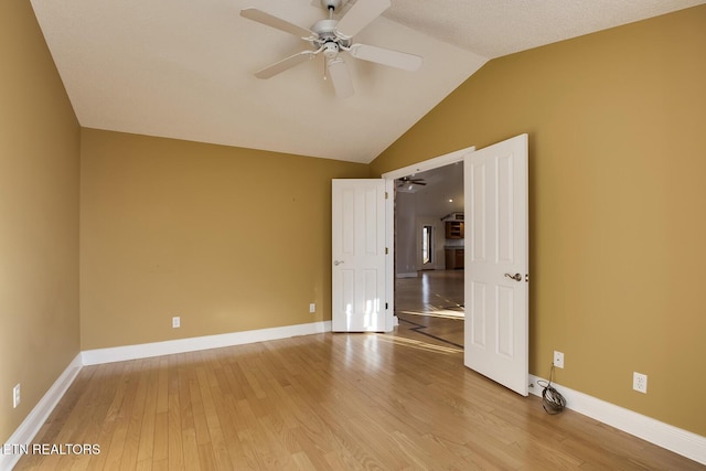 unfurnished room with lofted ceiling, light wood finished floors, ceiling fan, and baseboards