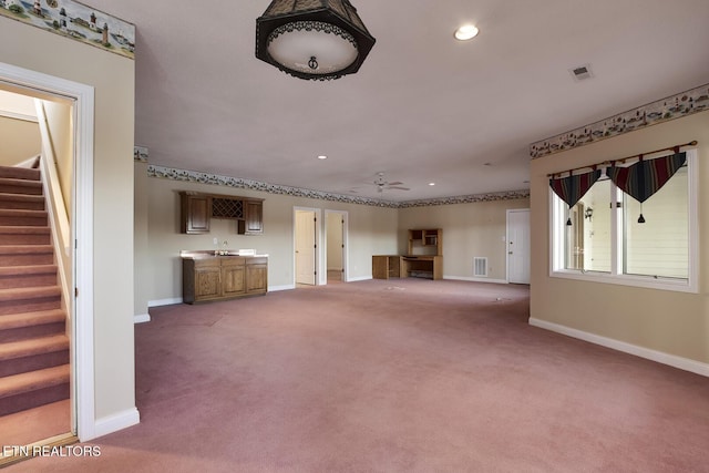 unfurnished living room with carpet flooring, visible vents, baseboards, and stairs