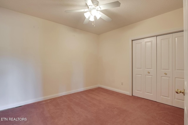 unfurnished bedroom with a closet, carpet flooring, ceiling fan, a textured ceiling, and baseboards