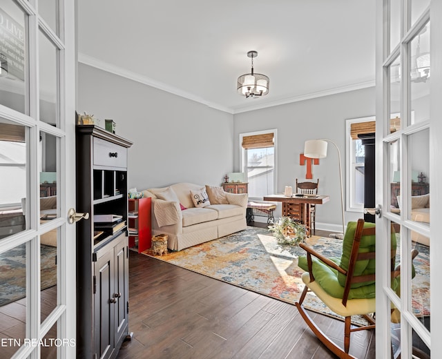 living room featuring dark wood-style floors, ornamental molding, and an inviting chandelier