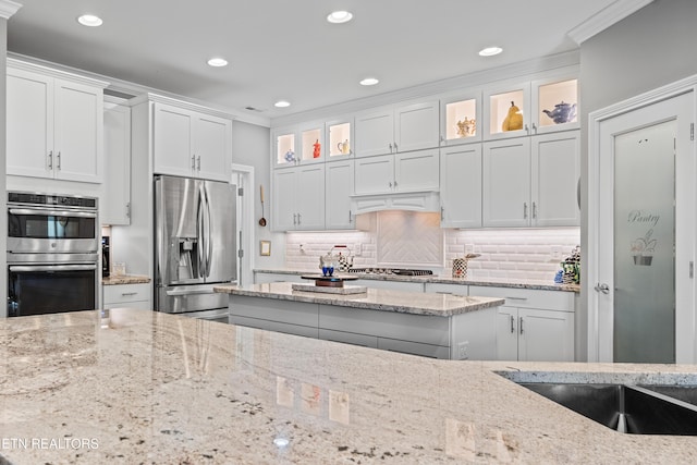 kitchen with white cabinetry, crown molding, appliances with stainless steel finishes, and backsplash