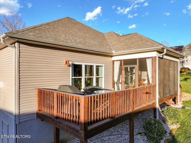 rear view of house with a shingled roof and a sunroom